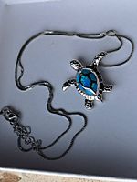 Front view of the sterling silver turtle pendant necklace with gemstone inlay on a white background.