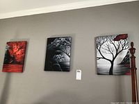 Photo showing the three canvas wall art paintings hung on a beige wall near a wooden bedpost