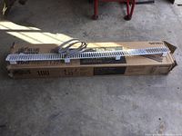 Blue Hawk carpet tack strip laying on a cardboard box with visible brand and product details; metal shelf front visible on top.