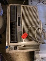 Beige Frigidaire window AC unit with front vent grill, display panel, and power cord.