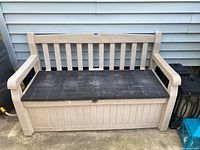 Front view of beige Keter outdoor storage bench with black lid, showing weathered and worn condition.