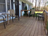 Photo showing the patio setup with four chairs, one glass top patio table, two plastic side tables, and two glass top nested side tables outside on wooden deck
