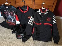 Lot contents laid on floor showing two racing jackets, one T-shirt, and one fanny pack.