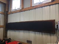 Full view of long, dark raw edge wood slab attached to a metal wall showing its length and width.