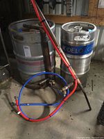 View showing two large stainless steel vessels, one labeled Troegs and the other Modelo Gran Reserva, with pipes and hoses connected.