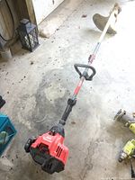 Full length side view of the Craftsman gas-powered string trimmer showing the trimmer head, shaft, and engine base on concrete floor.
