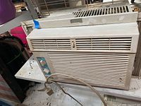 Front view of weathered white RCA window air conditioner with power cord and control panel visible.