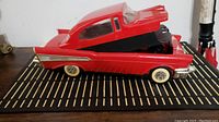 Side view of red 1957 Chevy VHS tape rewinder with top lid open revealing tape compartment.