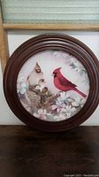 Front view of the round decorative plate displaying the cardinal family artwork with floral background.