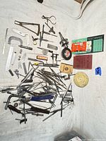 Overview photo of entire lot of vintage machinist tools arranged on white fabric, showing various measuring and hand tools scattered and grouped.