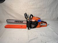 Front-right profile showing entire chainsaw with cover fitted.