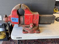Front and side view of the large antique Parker vise showing the handle, jaws, and base mounted on a table.