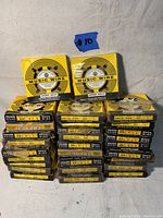 Photo showing 29 boxes stacked with the label #10 for identification. Boxes are black and yellow Precision Brand music wire.