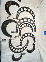 Lot of seven large micrometers and frames arranged on a white surface, including both full micrometers and frames only with circular cutouts in the frame.