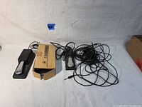 Two Yamaha volume pedals and one NFP1 pedal laid flat with assorted cables. One Yamaha pedal is in partially open Yamaha box.
