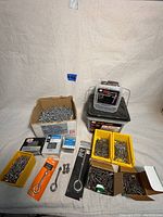 Full lot layout showing various boxes, bins, and packaging with screws, bolts, and hardware on gray cloth background.