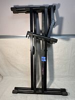 Folded black metal keyboard stand showing overall structure and foldability.