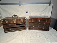Front view of both antique machinist tool boxes side by side showing their wood finish and latch hardware.