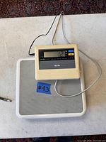 Full view of Tanita scale platform with connected digital display on top, showing part of the power and data cable.