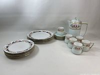 Full lot arranged showing plates, teacups with saucers, and jug from multiple angles to capture details of china design and shape.