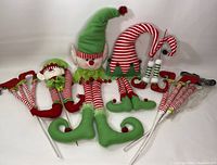 Full lot of elf-themed Christmas tree picks including elf heads, legs with curled shoes, and red and white striped elf legs with wire stems for wreath attachment.