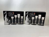 Two unopened black boxes of Grand Chateau cordial glasses shown side by side, front view with images of the glass designs and brand logo