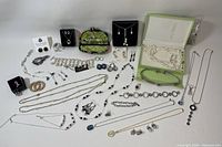 Overview of assorted jewelry including necklaces, earrings, bracelets laid out with storage items