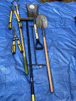 Set of 5 garden tools including shears, rake, shovel, and hoe laid out on a blue tarp.