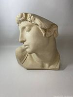 Front angle view of the white plaster bust of a classical male head resembling David