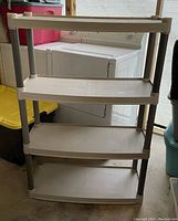 Front view of the four-tier plastic shelving unit showing all shelves and structure.