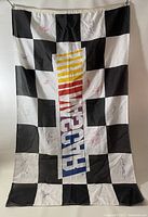 Full photo of NASCAR black and white checkered flag featuring NASCAR logo and multiple signatures