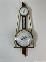 Full front view of the vintage weather station mounted on wood with brass casing showing barometer, thermometer and top gauge.