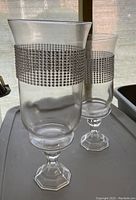 Two clear glass pedestal vases with octagonal bases and bands of rhinestone mesh around upper sections shown from side angle.