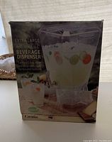 Front view of the beverage dispenser's original packaging showing product image and features.