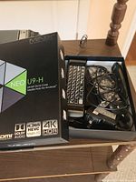 MINIX NEO U9-H product box with partial view of contents inside including keyboard, remote control, and power adapter