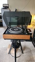 Front view of the Gerrard Model 4 turntable on a black tripod stand with dust cover open showing platter and tonearm.