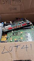 Box open showing multiple stacked circuit boards with electronic components for scrap recovery