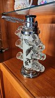 Side view of the vintage liquor decanter with silver leaf design and attached shot glasses