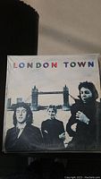 Front cover of the London Town vinyl album showing three men standing by Tower Bridge.