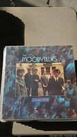 Front cover of Moody Blues Collection vinyl record album with band photo on a marbled blue/black background.