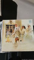 Vinyl record with album cover showing four individuals in white uniforms and hats standing in a staged pose.