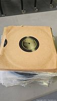 Stack of approximately 40 vintage 78 RPM records in brown paper sleeves with visible wear and age
