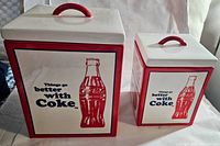 Full view of two square Coca Cola nesting canisters with lids showing 'Things go better with Coke' and classic Coke bottle illustration