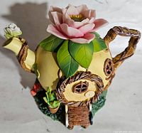 Front and side view showing door, window, flower on top, and base decorations including buttons and spool of thread.