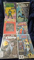 Photo of 6 DC Comics comic books laid out showing covers of Green Lantern, The Question, Robin, Valor, Detective Chimp, and Justice League Europe.