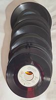 Top view of a stack of 7-inch 45 RPM vinyl records showing black vinyl discs with center labels partially visible.