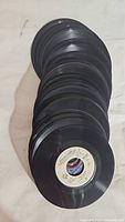 Stack of multiple 7-inch 45 RPM vinyl records showing black grooves and paper labels.