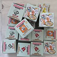 Top-down view showing a pile of Monopoly Surprise Collectible Token boxes, each with the Monopoly logo and 'Peel & Reveal' prompt.