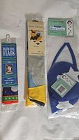 Photo of three decorative flags still in packaging and one package with blue wind twirler.