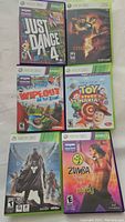 Photo showing six Xbox 360 video games including Just Dance 4, Resident Evil 5, Wipeout In The Zone, Toy Story Mania!, Destiny, and Zumba Fitness.